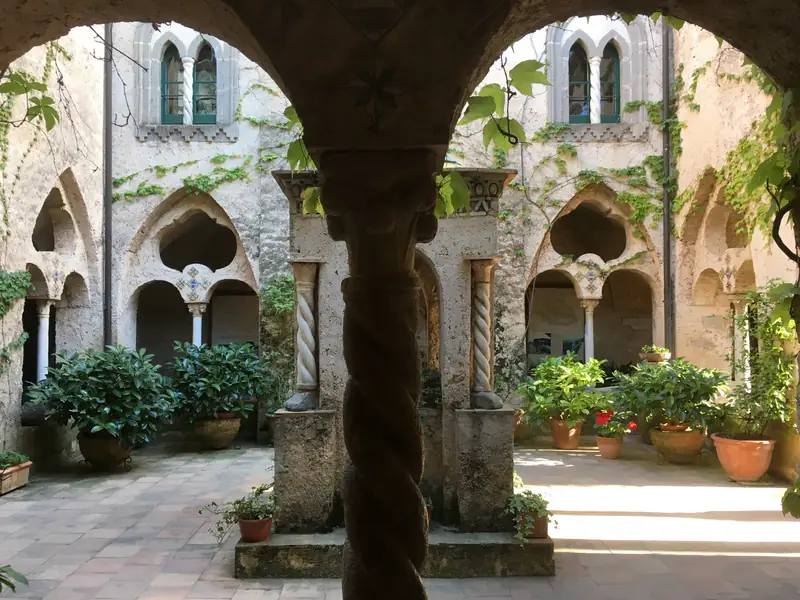 The cloister of Villa Cimbrone in Ravello, with Gothic arches and potted plants