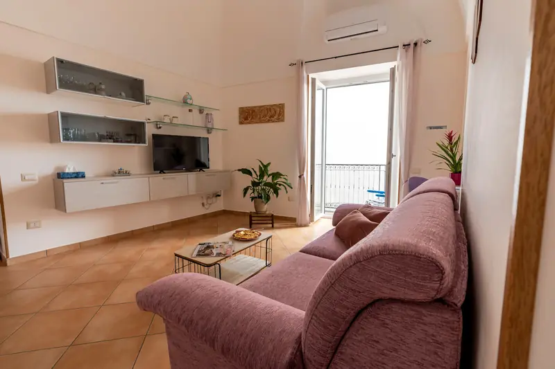 Soggiorno con divano letto e porta finestra sul balcone